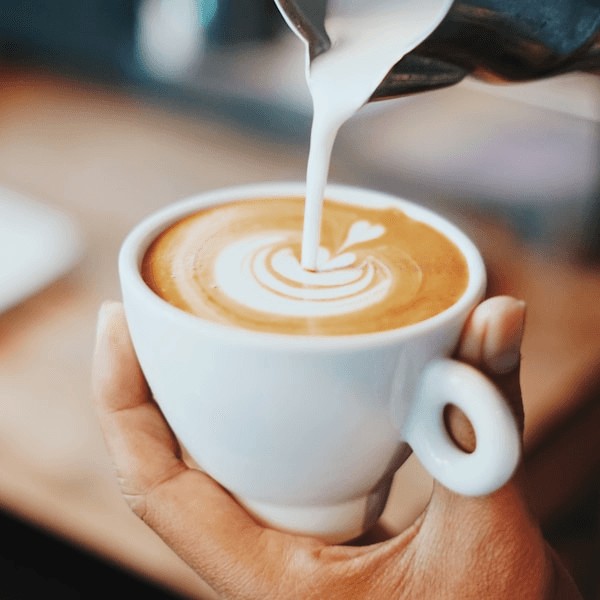 Barista pouring milk into a latte